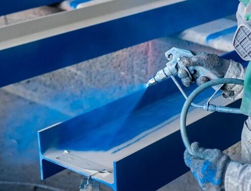 Application au pistolet d’une peinture anticorrosion sur une poutre en acier décapé